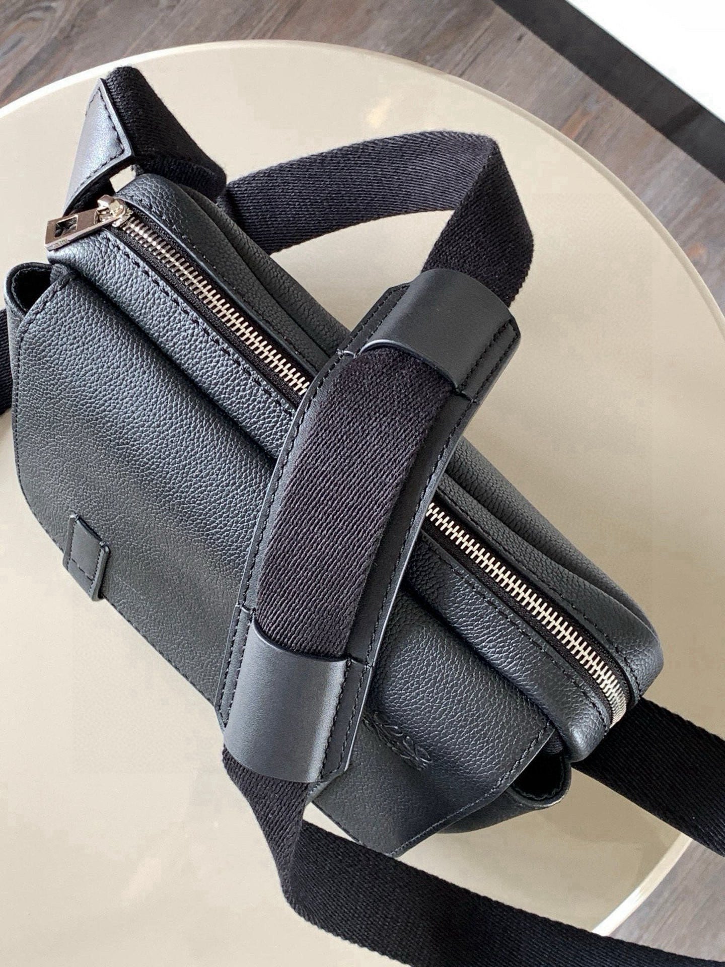 Dark leather sling bag with zip closure and adjustable crossbody strap