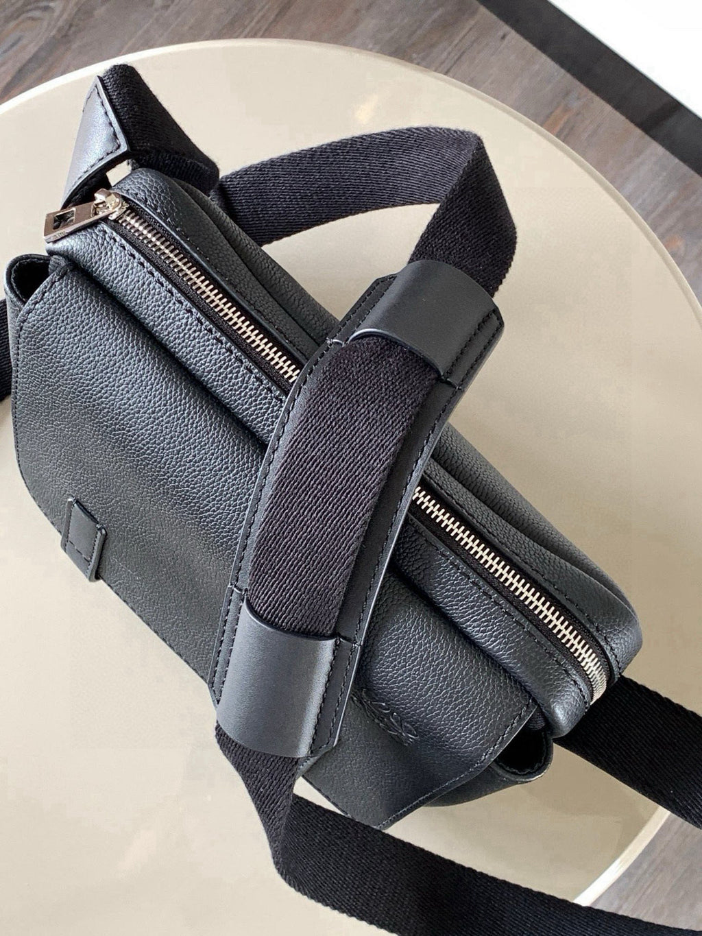 Loewe leather crossbody bag with zipper opening, front buckle straps, and shoulder strap.