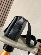 Dark leather crossbody bag with curved front panel and wide shoulder strap