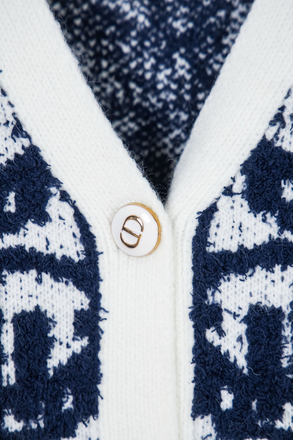 Knit cardigan button with gold D emblem on white trim
