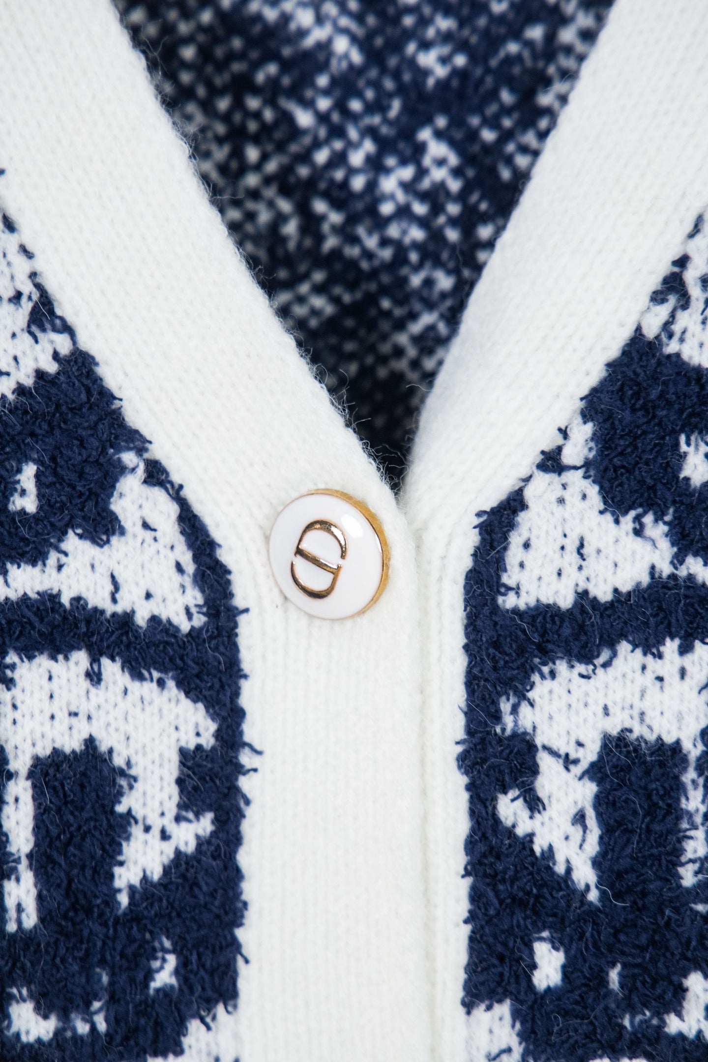 Knit cardigan button with gold D emblem on white trim