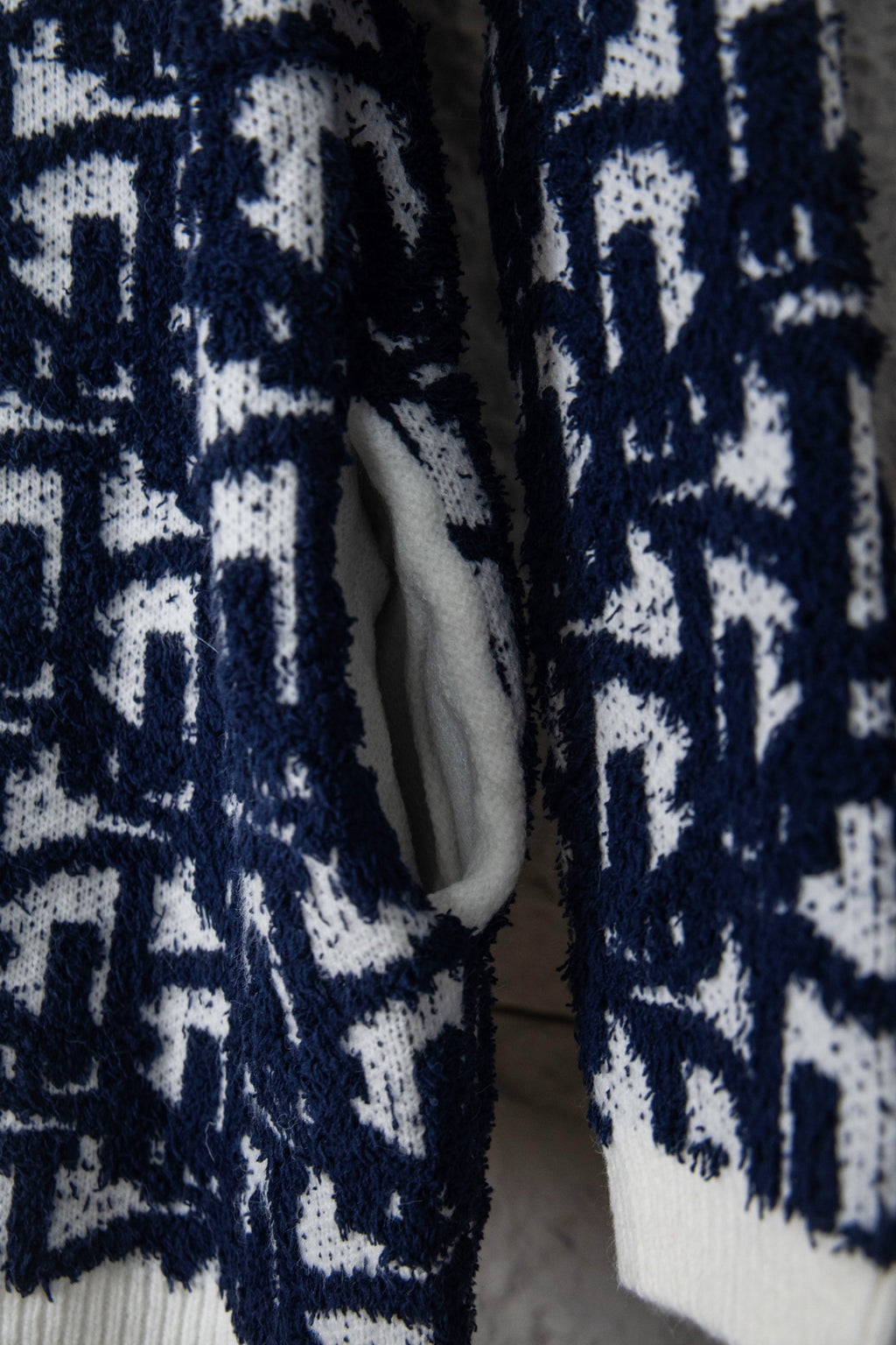 Open knit cardigan with navy-and-white pattern and light inner lining