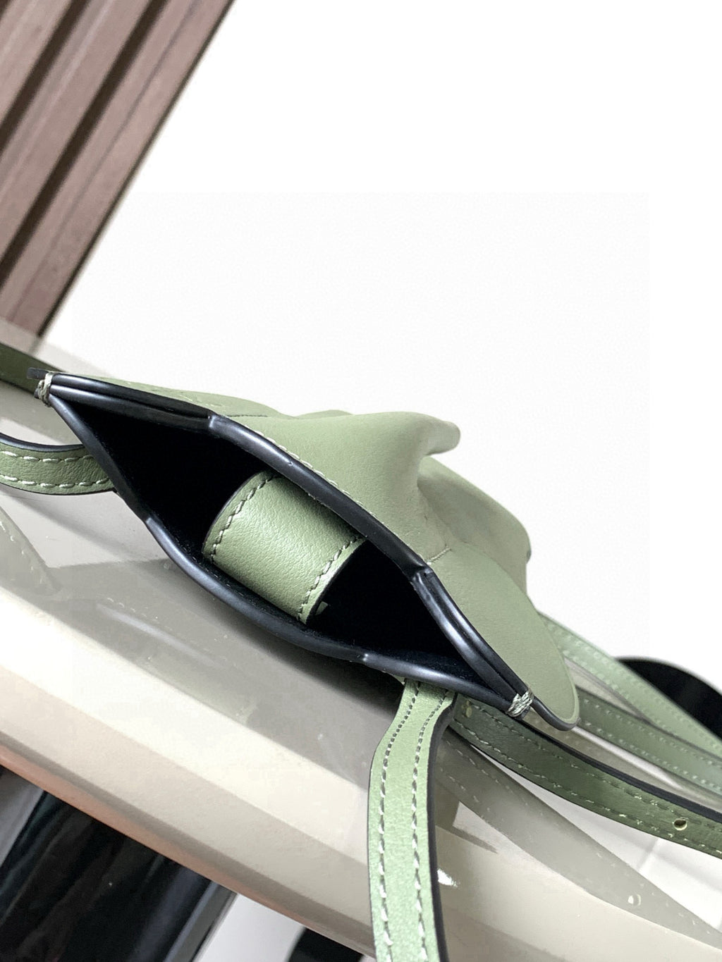 Mint green leather mini bag shown from side with adjustable strap and top handle