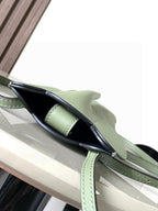 Mint green leather mini bag shown from side with adjustable strap and top handle