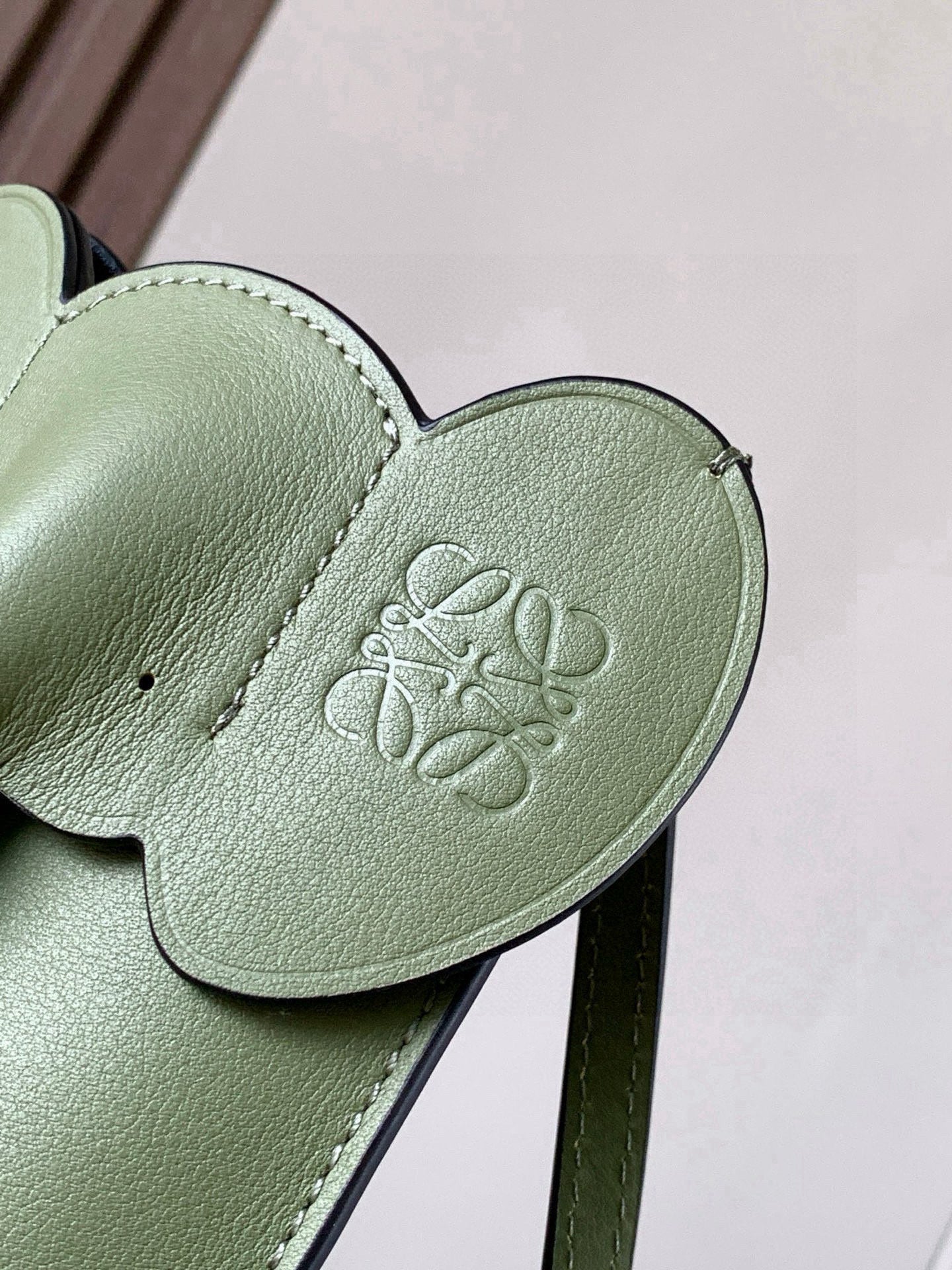 Mint green leather bag flap with embossed logo and stitched edge trim
