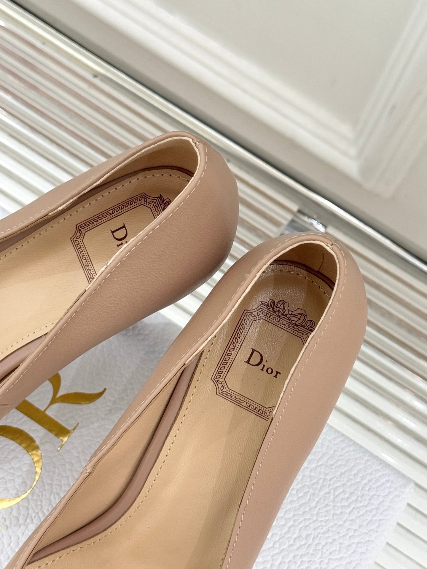 Beige Dior pointed-toe stiletto pumps with printed Dior label inside the shoe