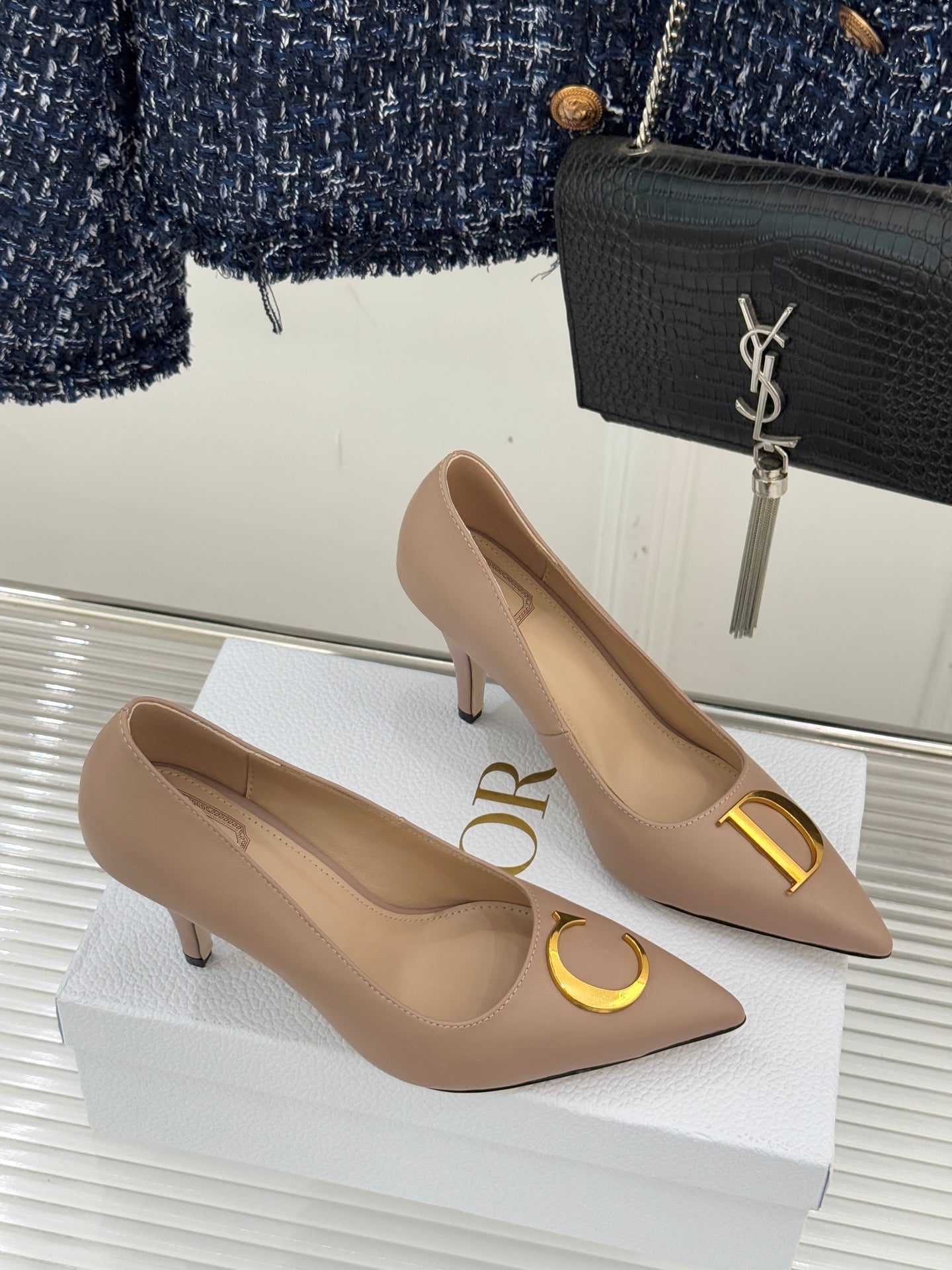 Beige Dior pointed-toe stiletto pumps pair with gold logo details, angled view