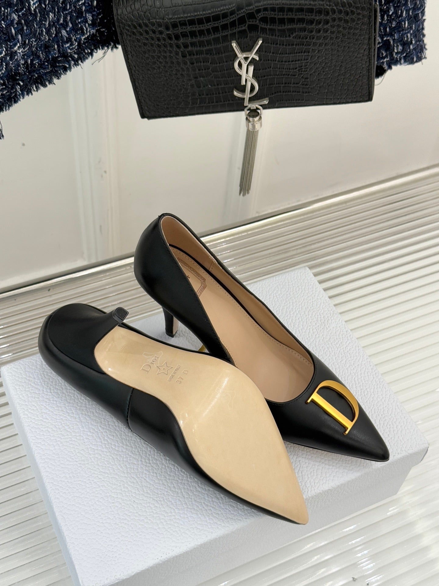 Black pointed-toe pumps with gold D logo and tan interior