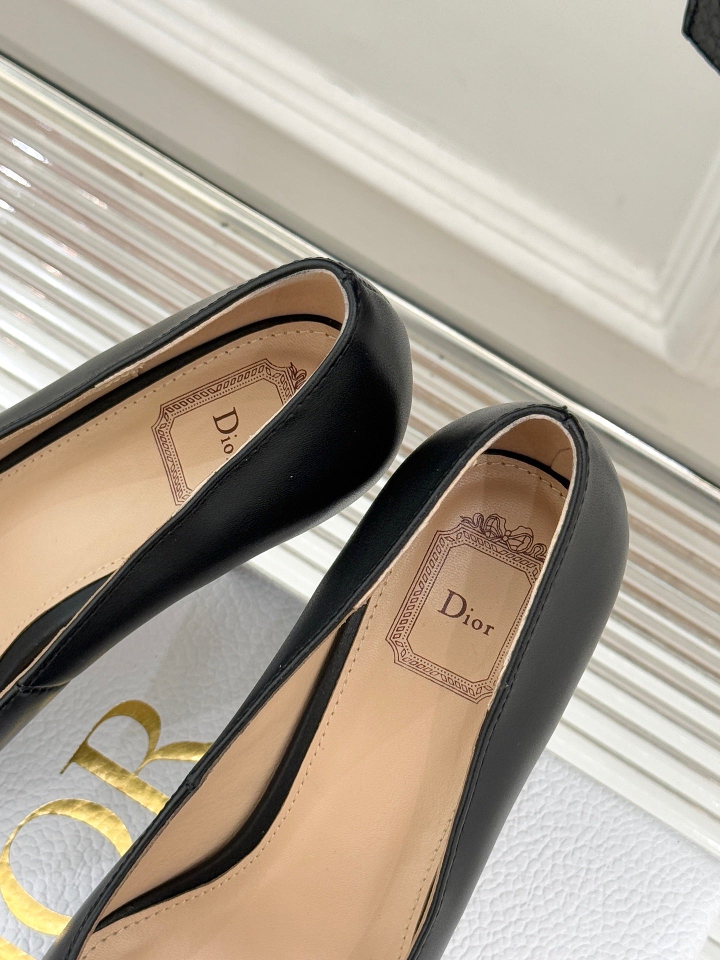 Black pointed-toe pumps showing tan insole and Dior-branded lining