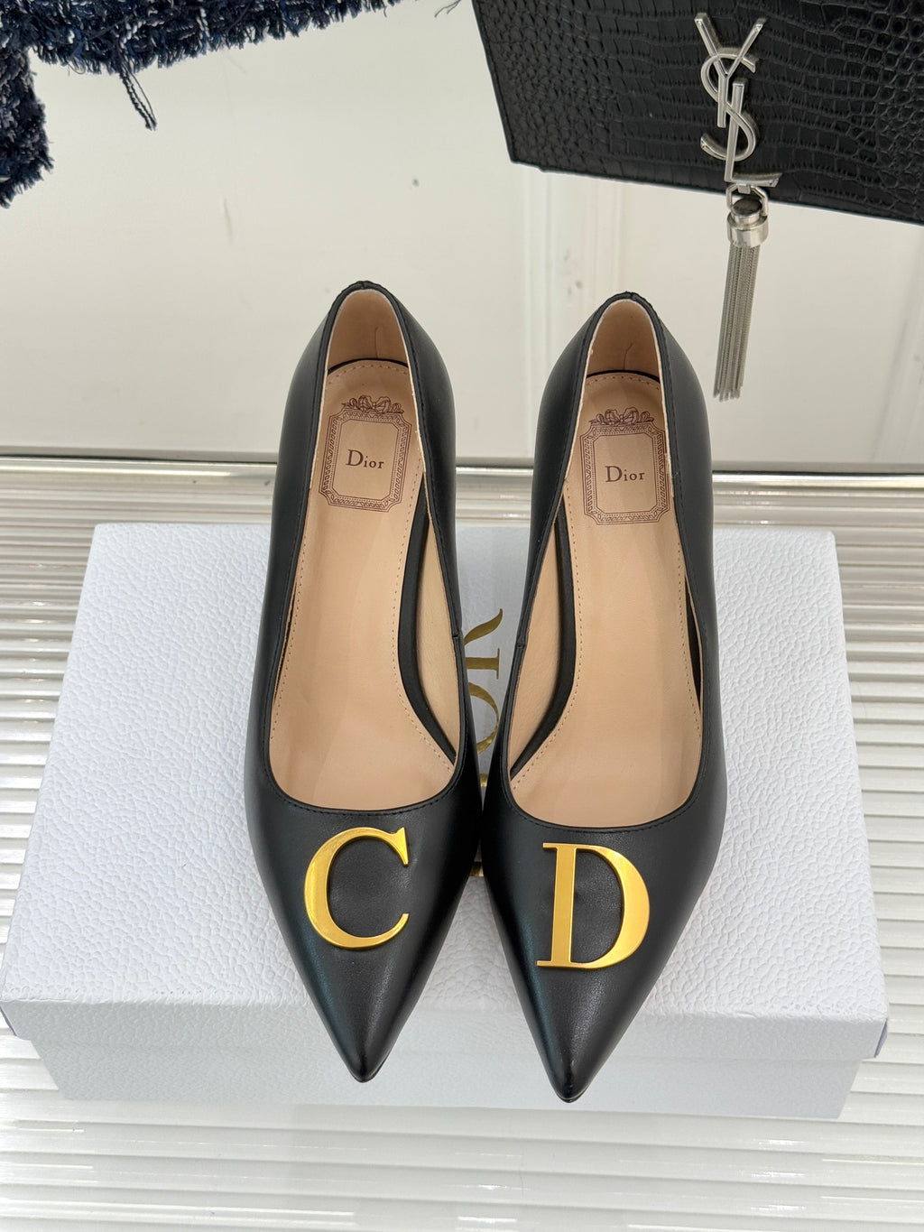 Black pointed-toe pumps with tan insole and gold C and D logo details