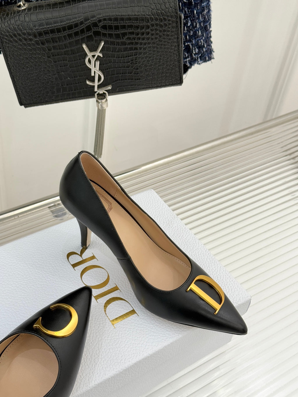 Black pointed-toe pumps with gold D emblem and slim stiletto heel