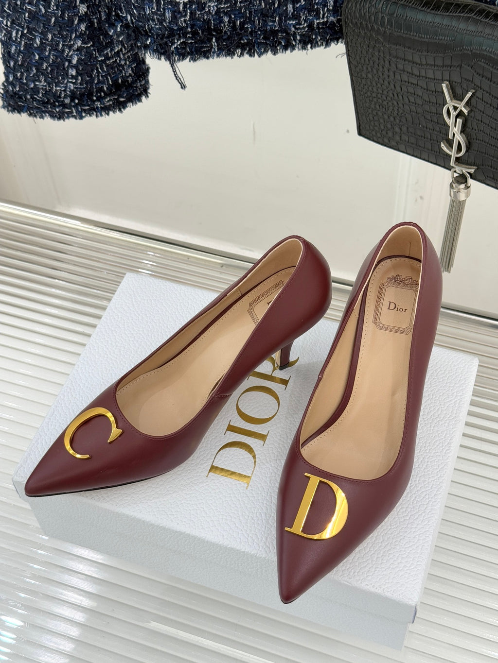 Maroon pointed-toe stiletto pumps on white display, gold logo accents