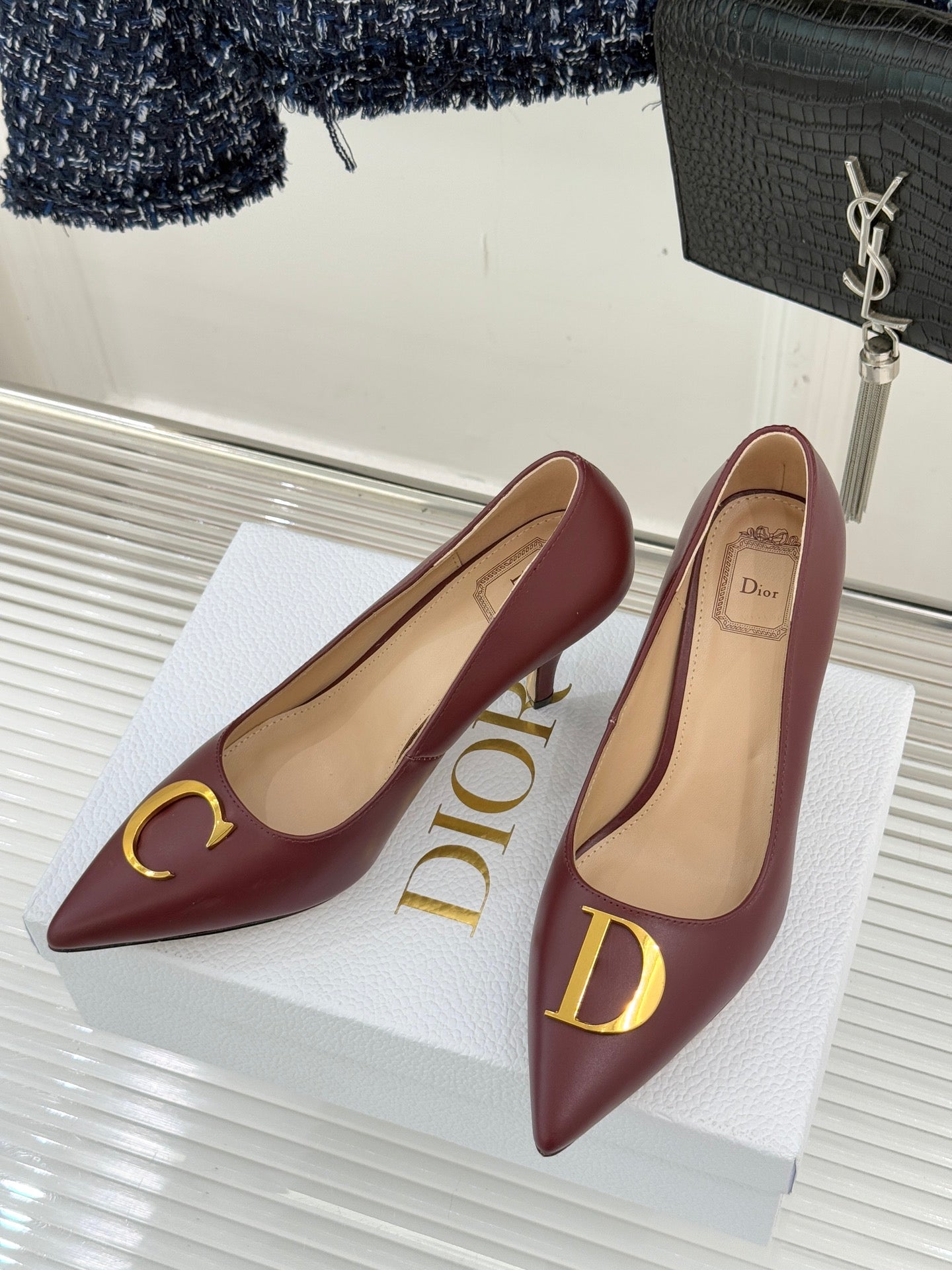 Maroon pointed-toe stiletto pumps on white display, gold logo accents