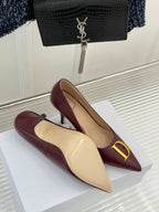 Maroon pointed-toe stiletto pumps with gold D accent on white display