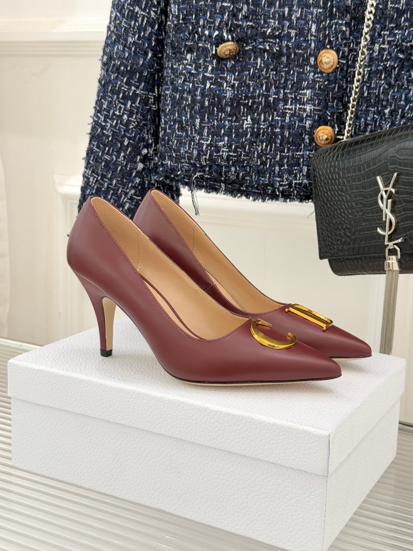 Maroon pointed-toe stiletto pumps with gold C-shaped logo detail