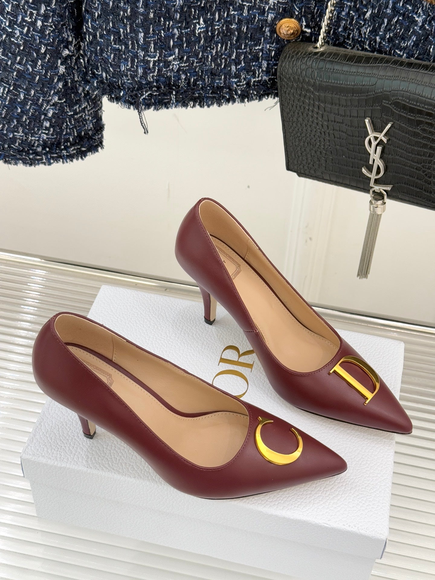 Maroon pointed-toe stiletto pumps with gold D and C emblem on vamps