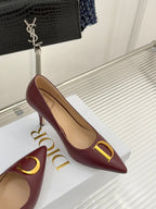 Maroon pointed-toe stiletto pumps with gold C and D logo accents, side view