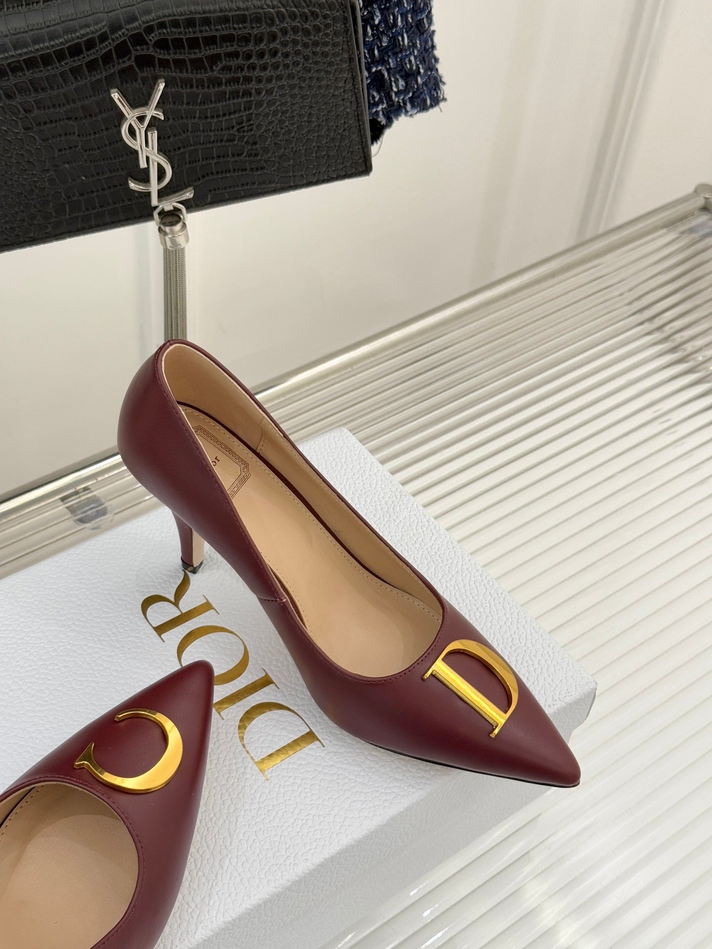 Maroon pointed-toe stiletto pumps with gold C and D logo accents, side view