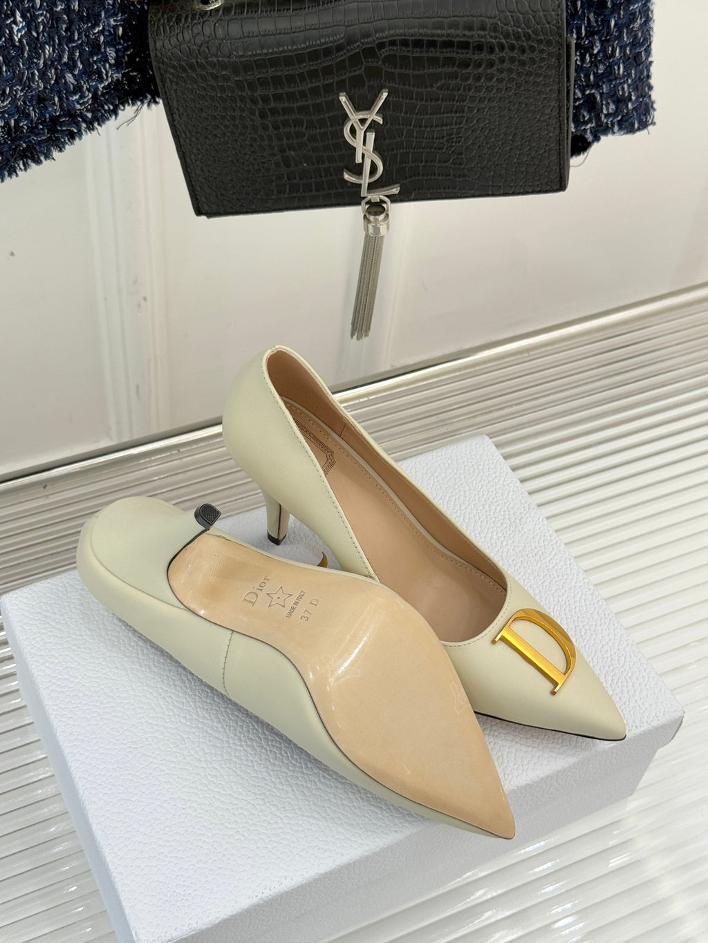 Cream pointed-toe high-heel pumps with gold D ornament and stiletto heel