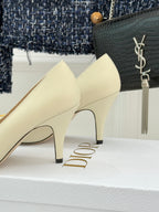 Cream pointed-toe high-heel pumps with slender heel and gold D emblem