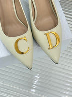 Cream pointed-toe high-heel pumps with gold C and D logo emblems