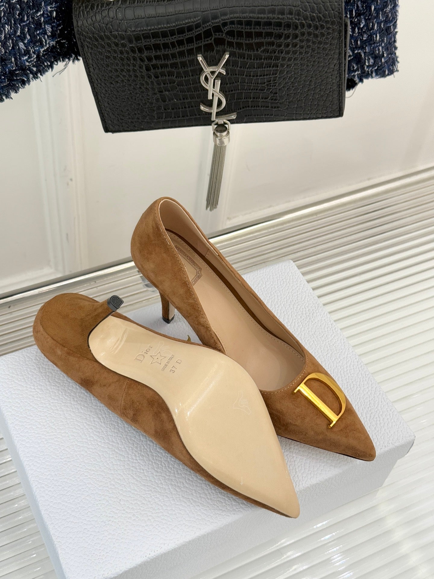 Tan suede pointed-toe stiletto pumps with gold D emblem and cream lining
