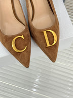 Tan suede pointed-toe pumps with gold C and D logo emblems