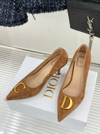 Tan suede pointed-toe stiletto pumps with gold C emblem on the vamp
