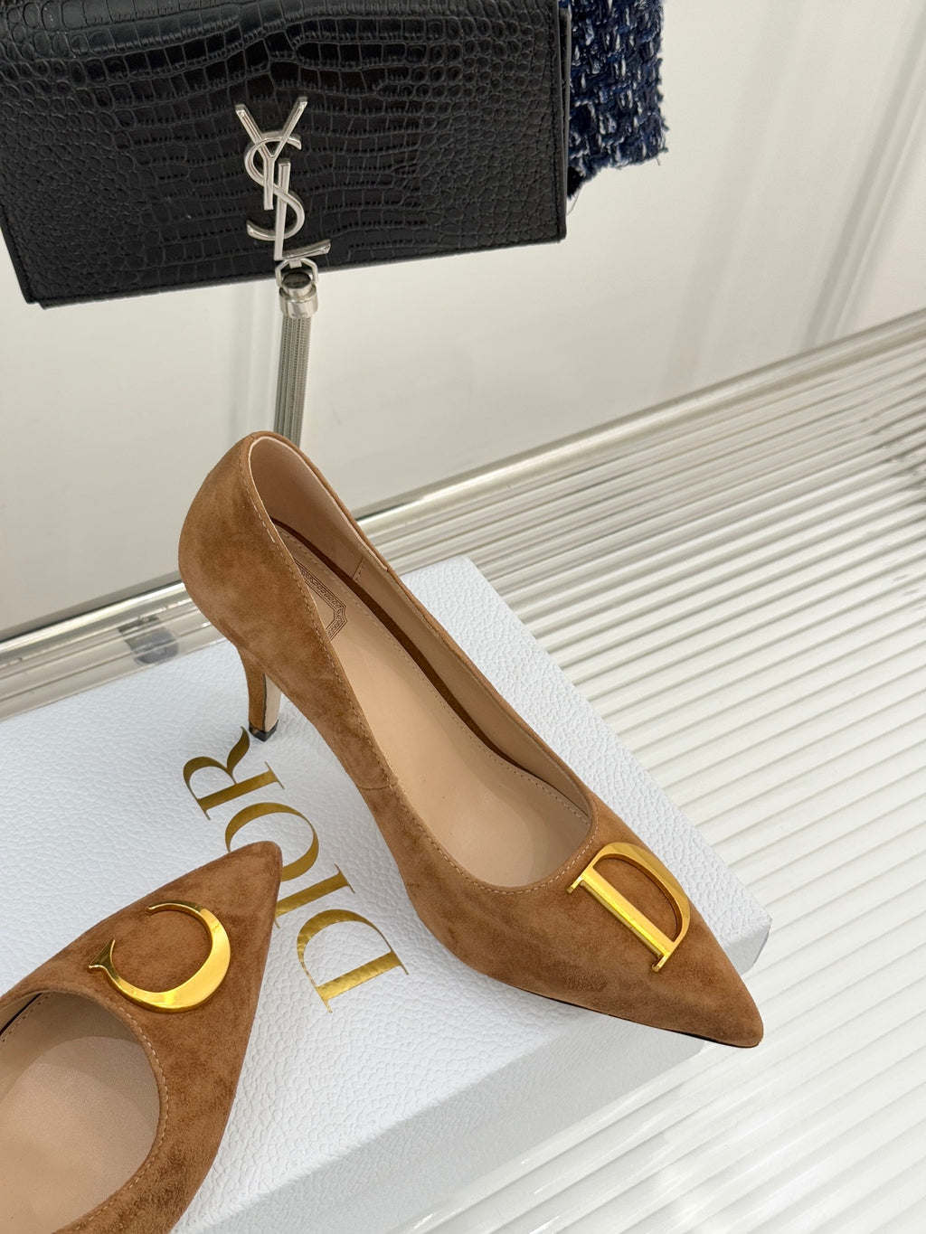 Tan suede pointed-toe pump with gold D emblem and stiletto heel