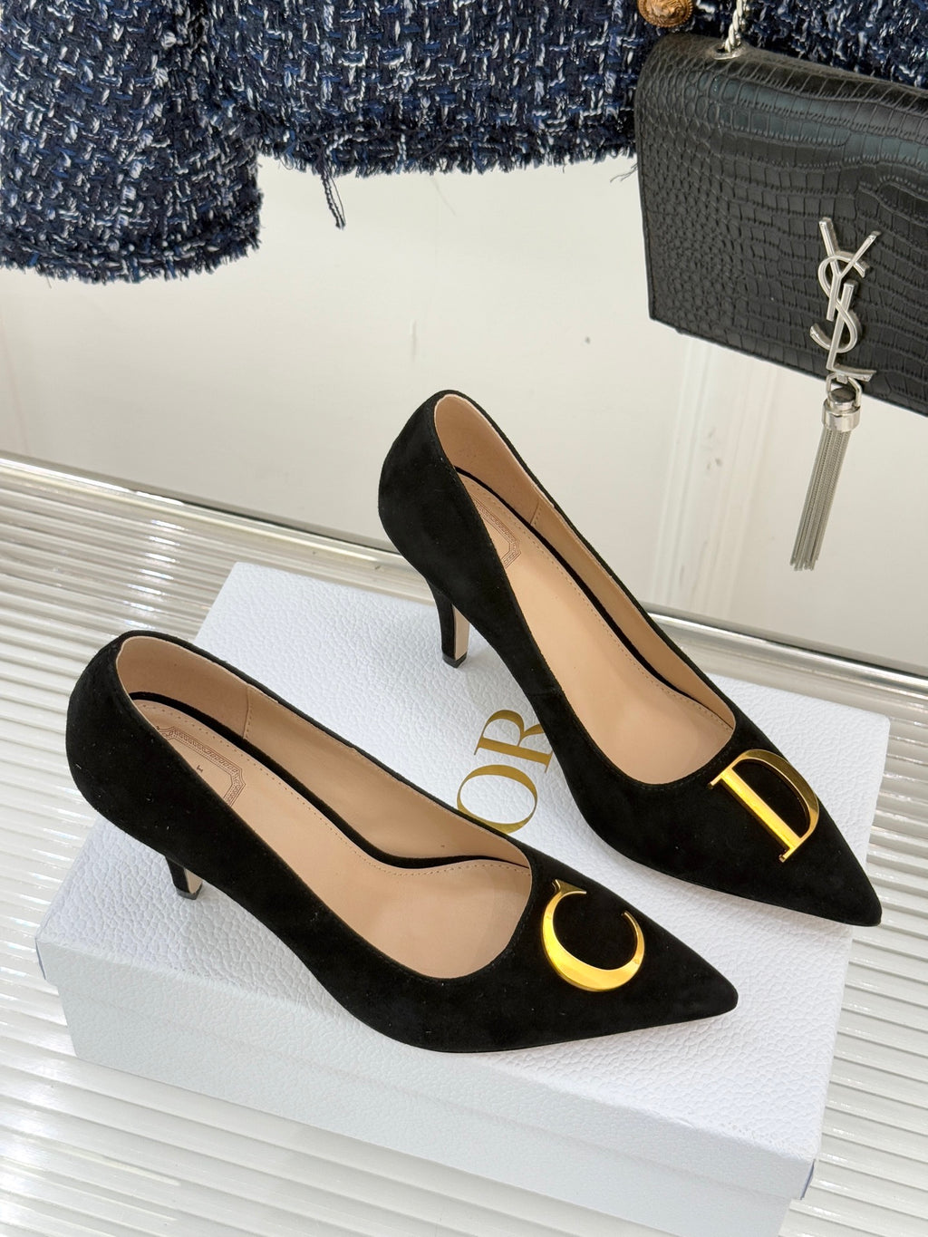 Black suede stiletto pumps with gold logo detail on toe