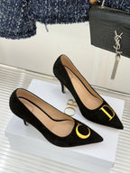 Black suede stiletto pumps with gold logo detail on toe