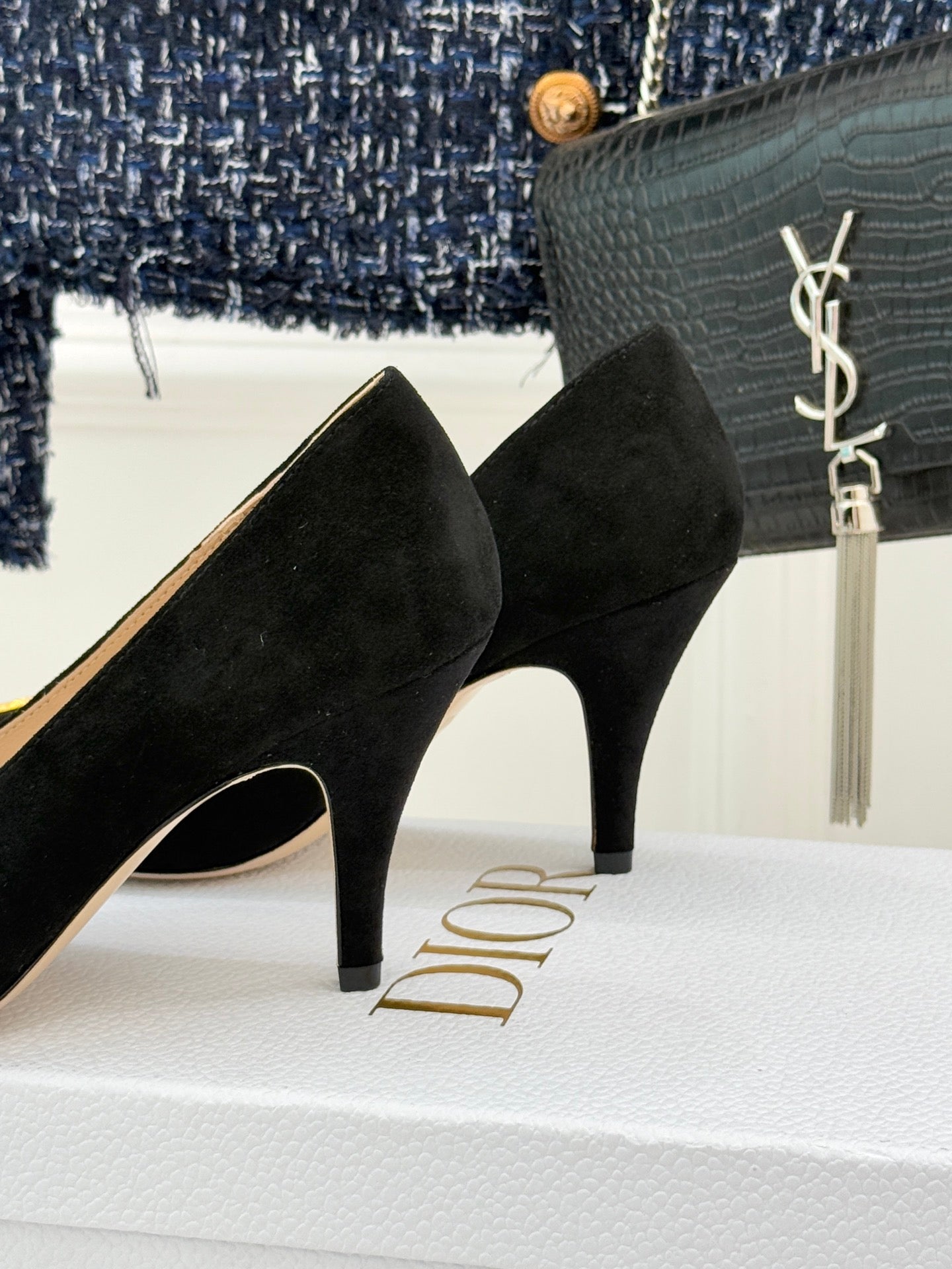 Black suede stiletto pump heel view with gold logo on platform