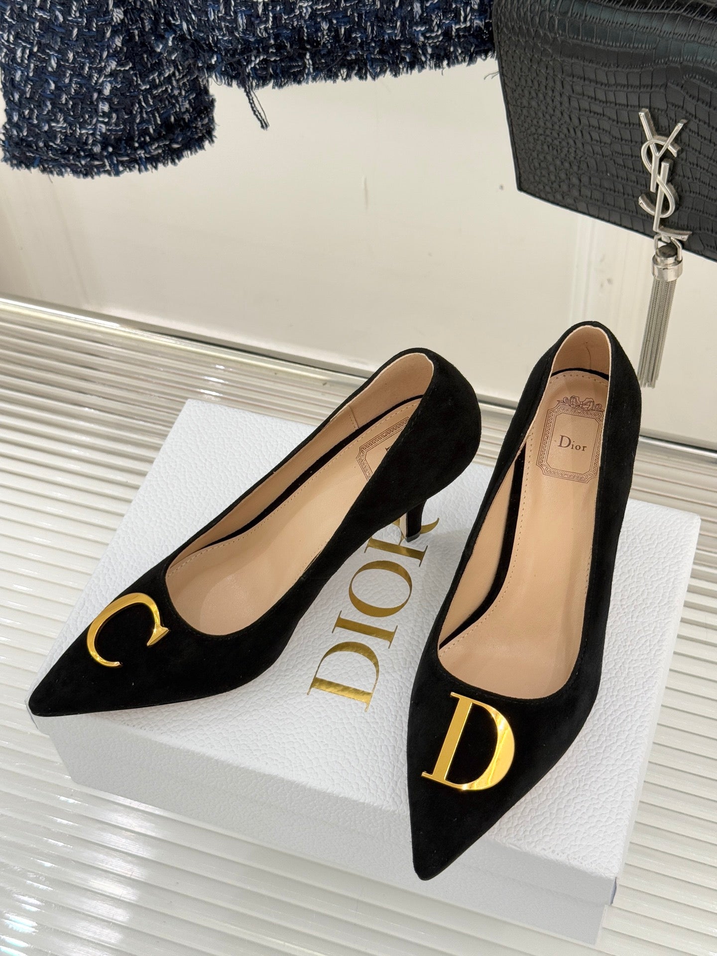 Black suede stiletto pumps on white box with Dior branding