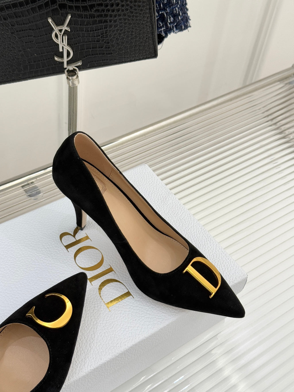 Black suede pointed pumps with gold logo accent and stiletto heel