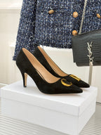 Black suede stiletto pumps with gold logo trim