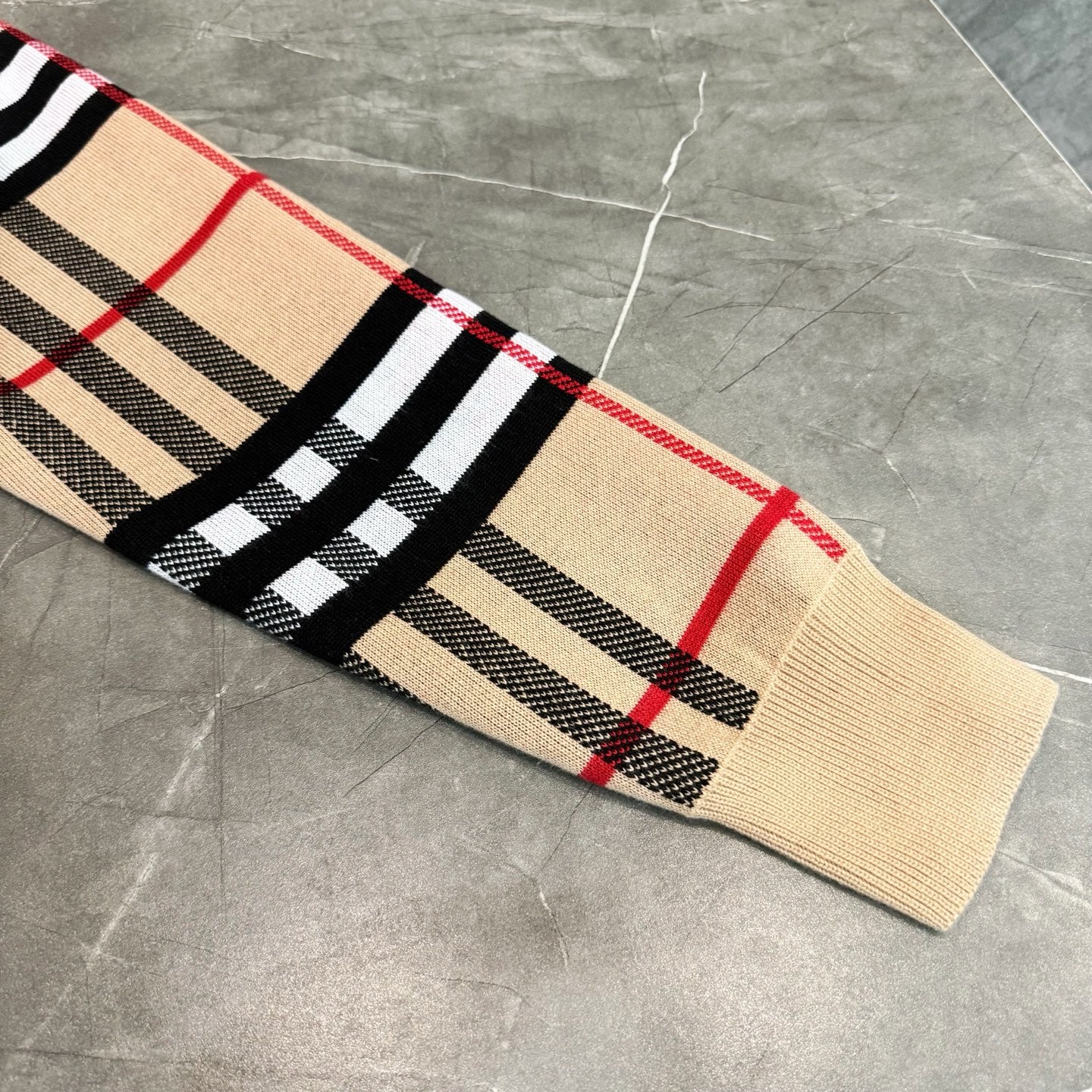 Beige knit plaid hoodie sleeve and hem with black, red, and striped pattern