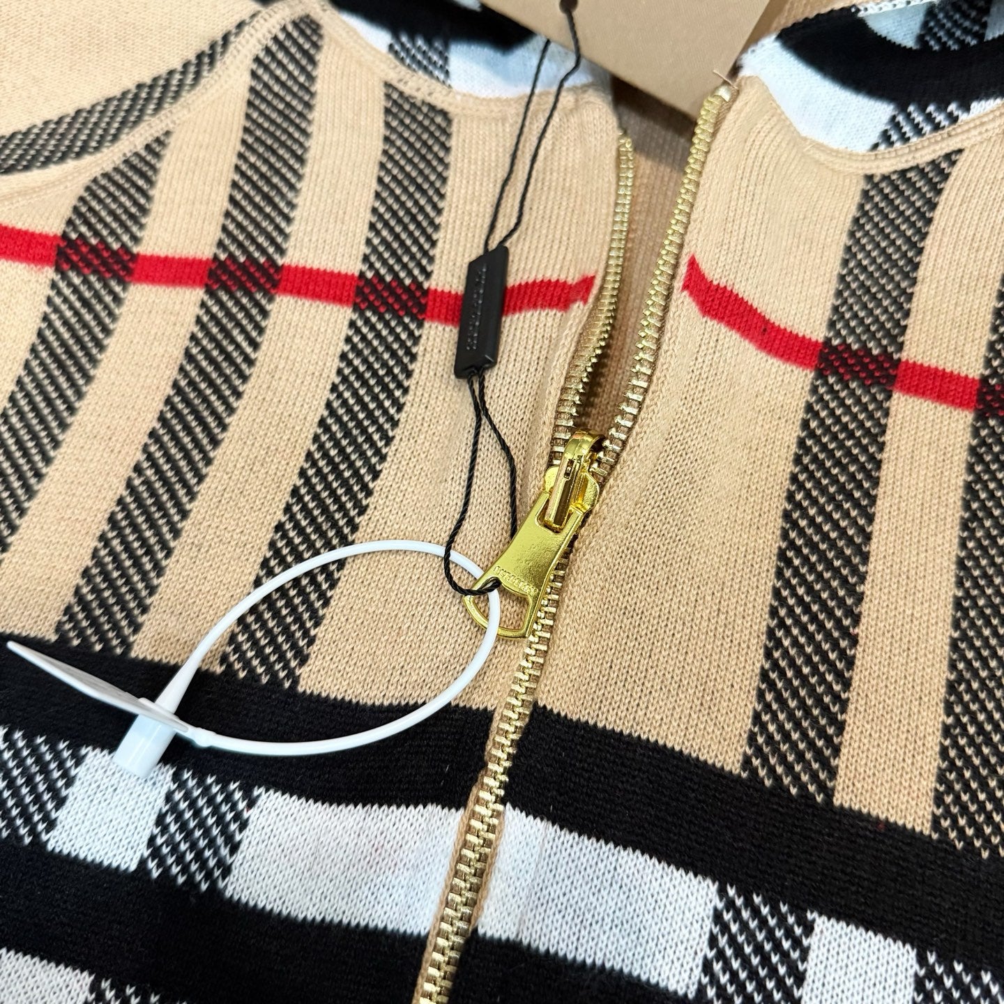 Plaid long-sleeve zip hoodie detail with gold zipper and drawstring cord
