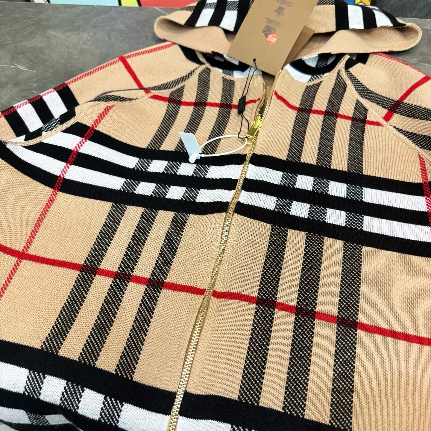 Plaid long-sleeve zip hoodie with hood, gold zipper, and red stripe lines