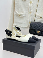 Chanel ladies' pointed flats in cream with black toe, pearl-and-bow embellishment