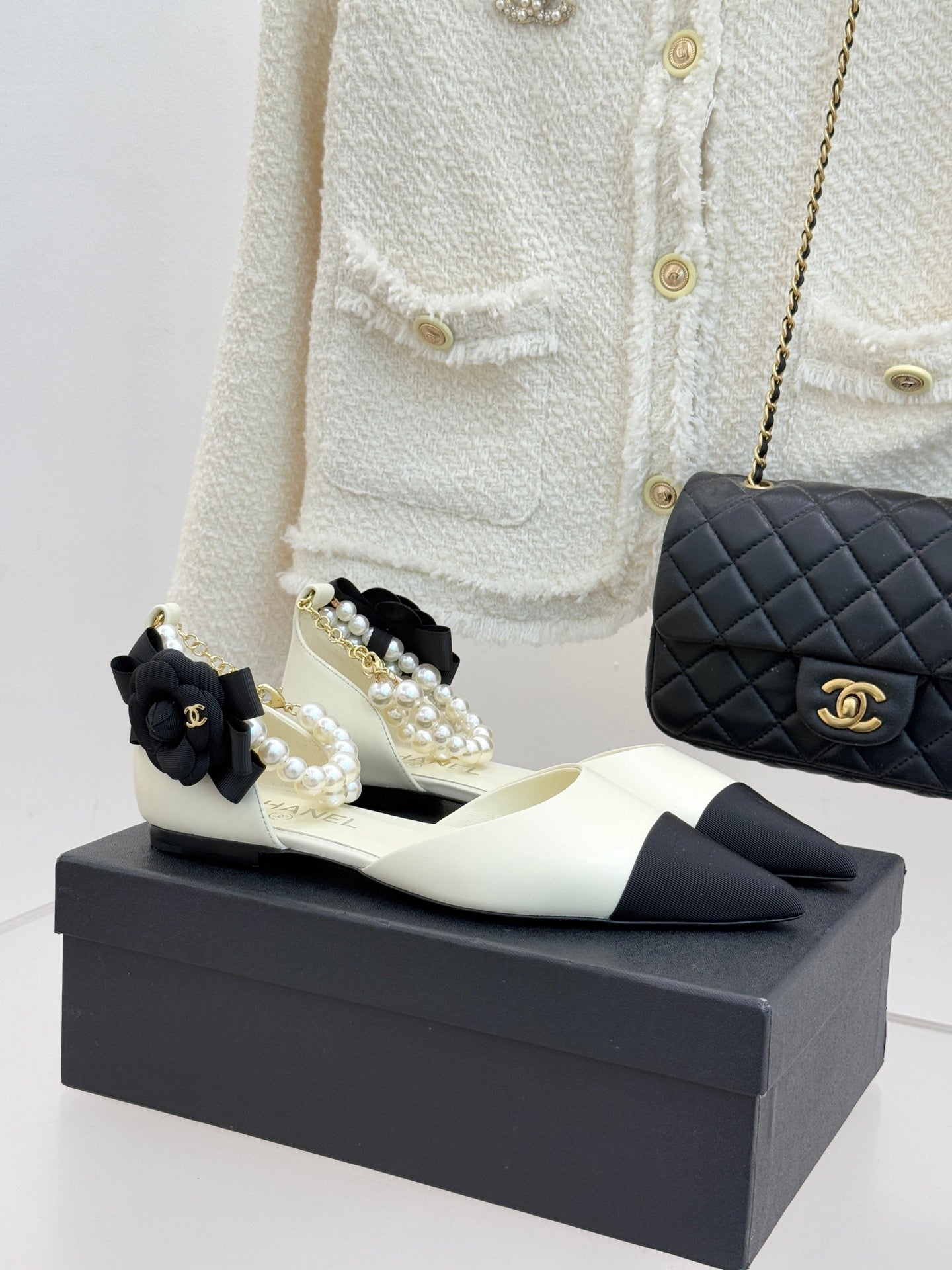 Chanel ladies' pointed flats in cream with black toe, pearl-and-bow embellishment