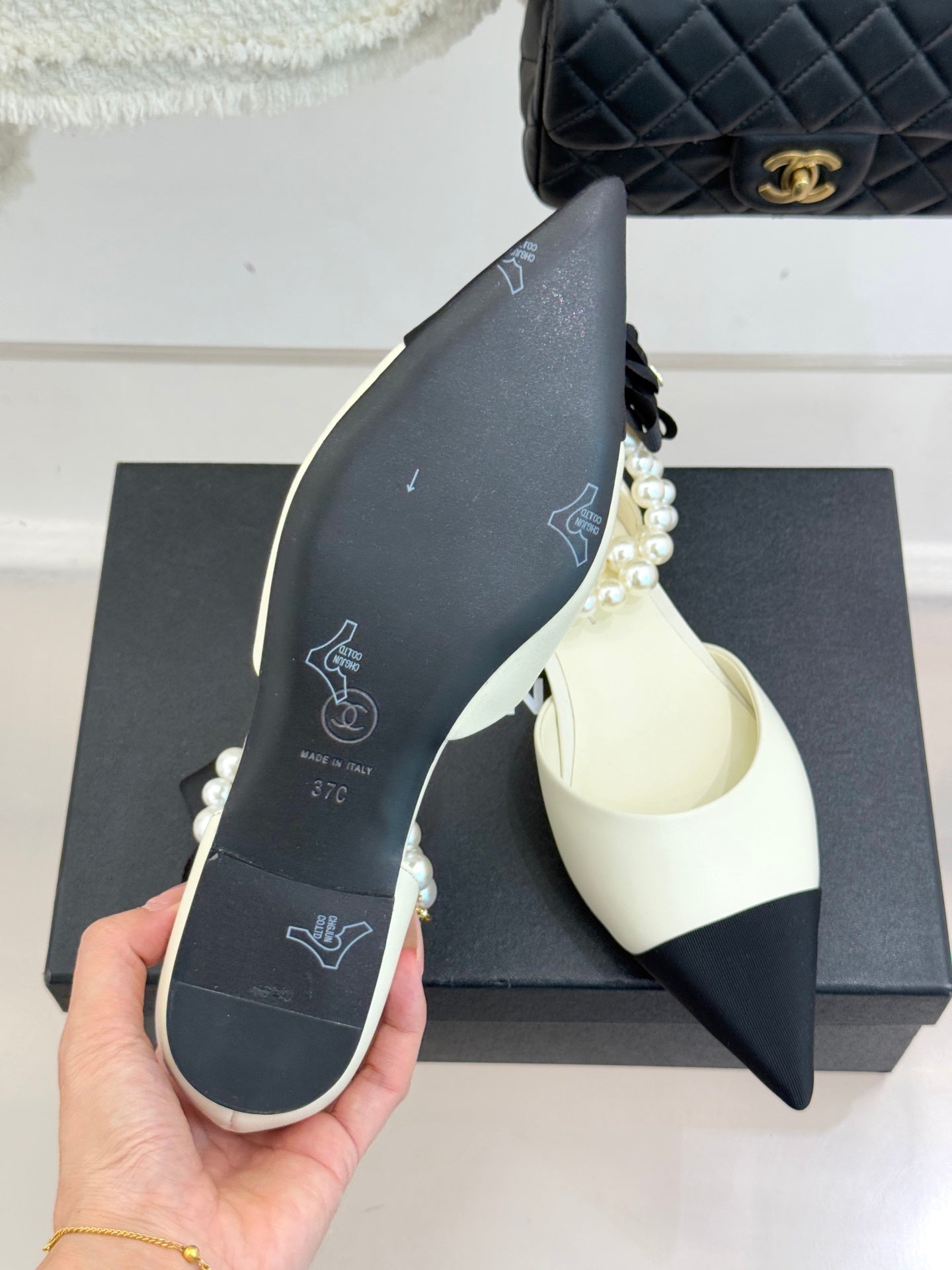 Chanel ladies' cream pointed flats with black toe band and pearl trim, sole shown