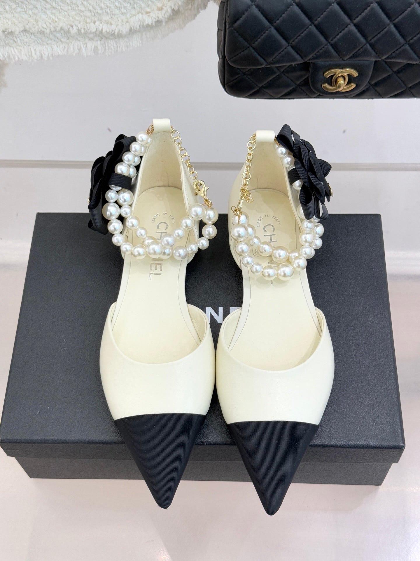 Chanel ladies' cream pointed flats with black heel tips and pearl bow strap detail