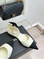Chanel ladies' cream pointed flats with black toe band and pearl-and-bow trim