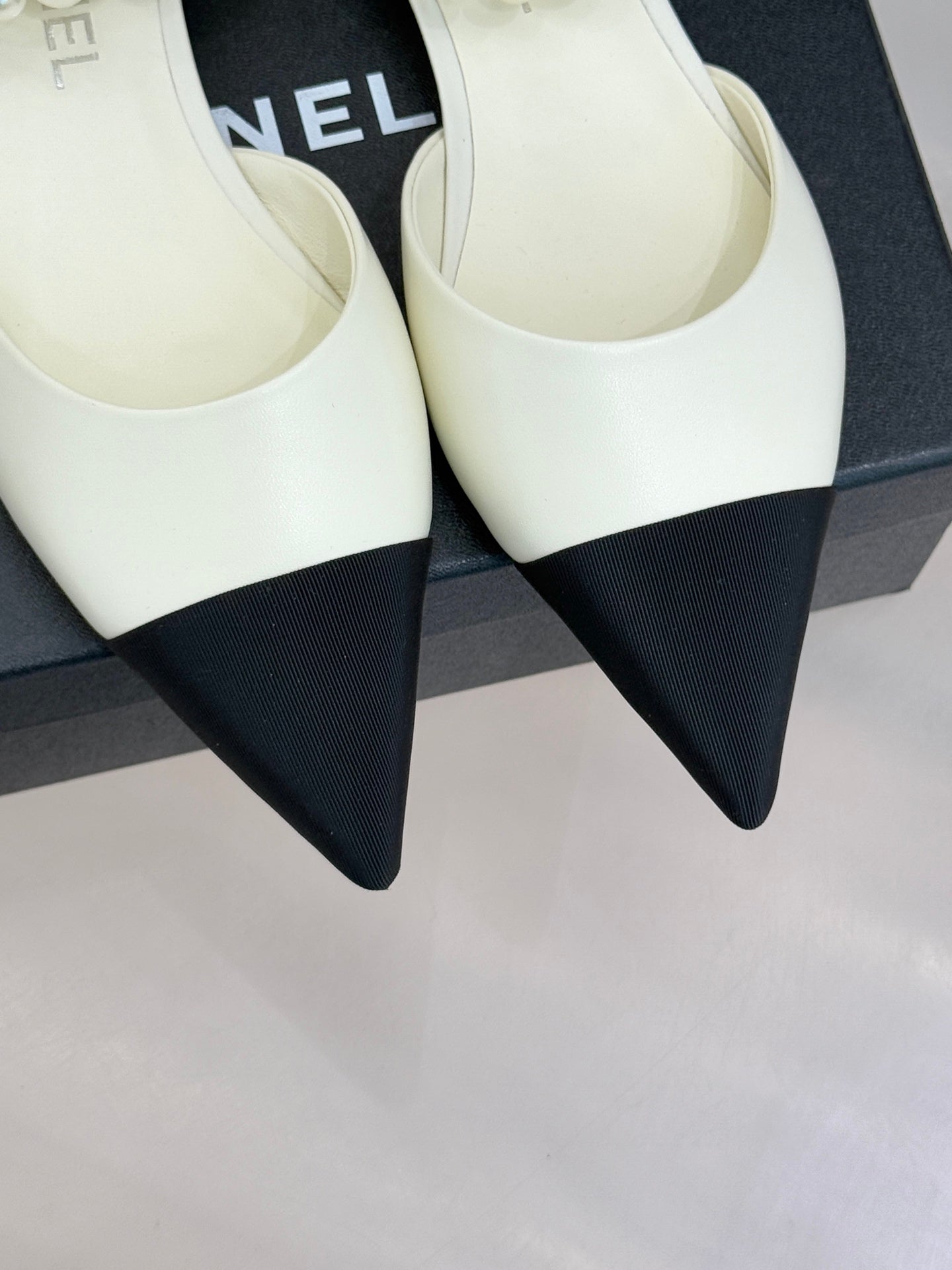 Chanel ladies' cream pointed flats with black toe accents, on a box