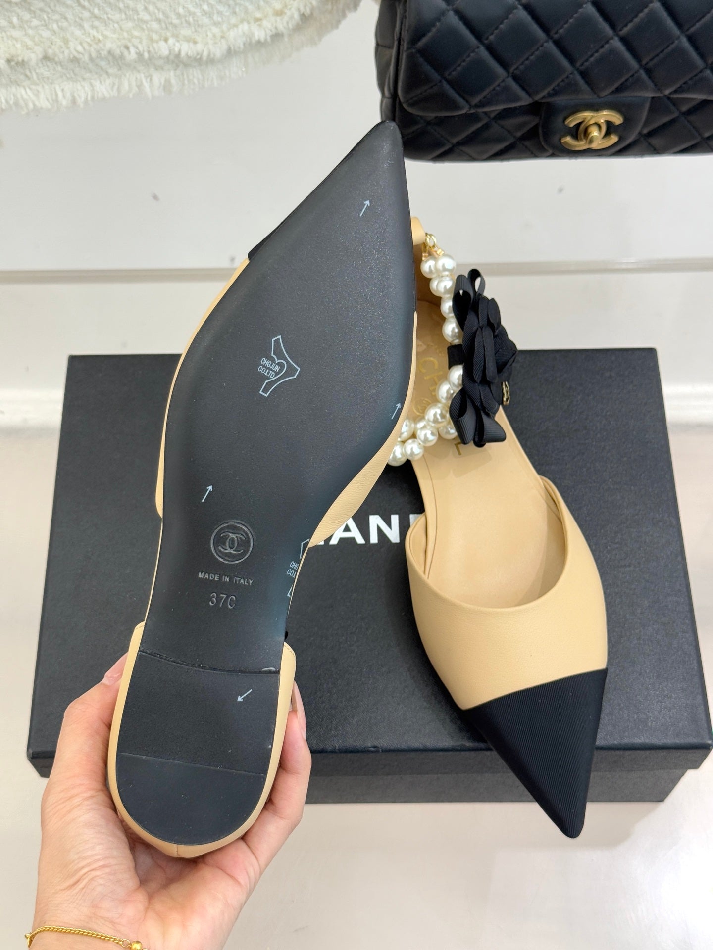 Shoe sole of Chanel beige pointed flats with black exterior and gold branding