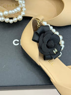 Close-up of Chanel beige flat with black bow, faux pearls, and gold chain detail