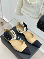 Chanel beige pointed-toe flats with black bows, faux pearls, and gold-tone hardware