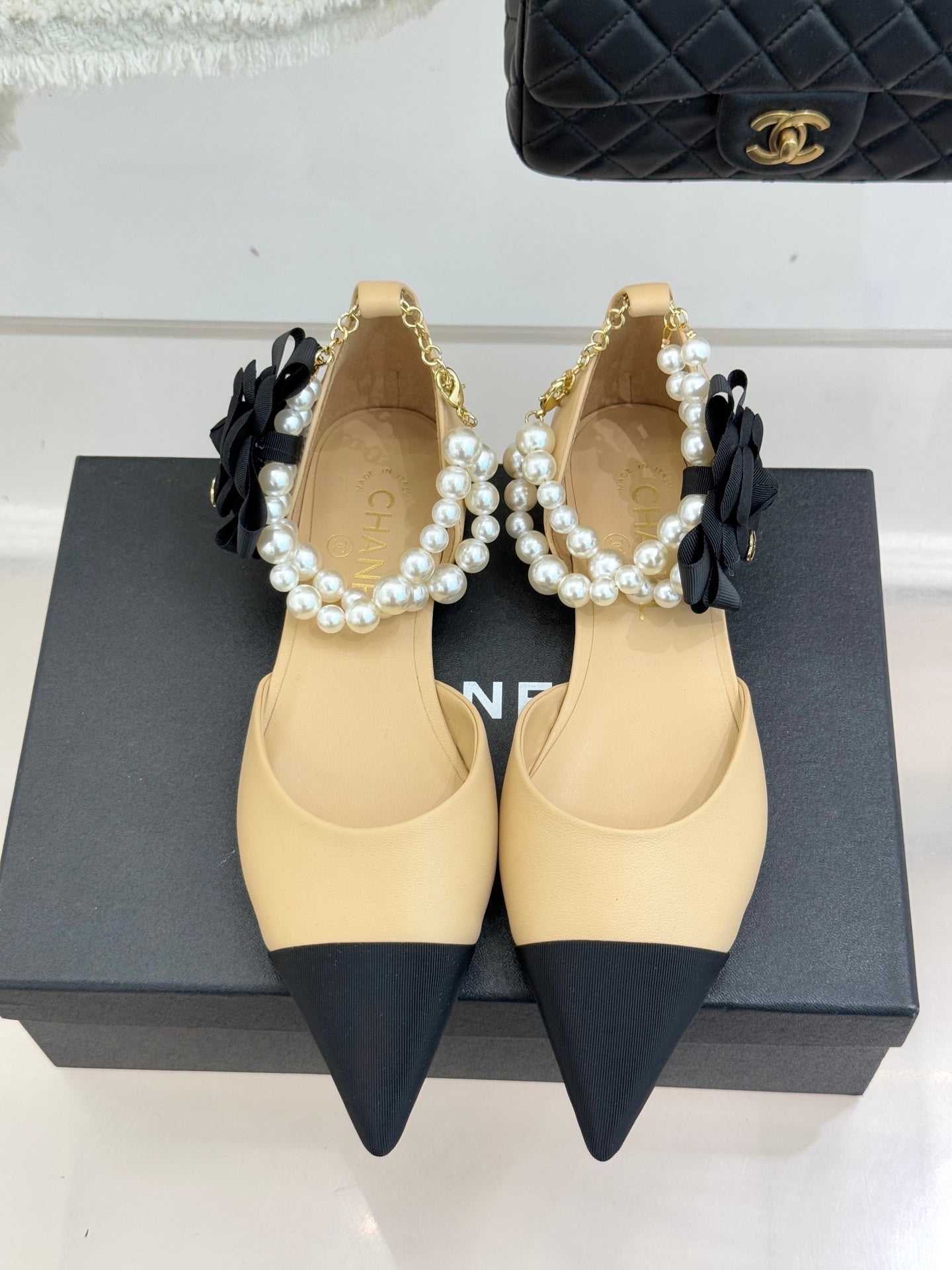 Chanel flats, beige pointed toes with black bow detail and faux pearl trim on display