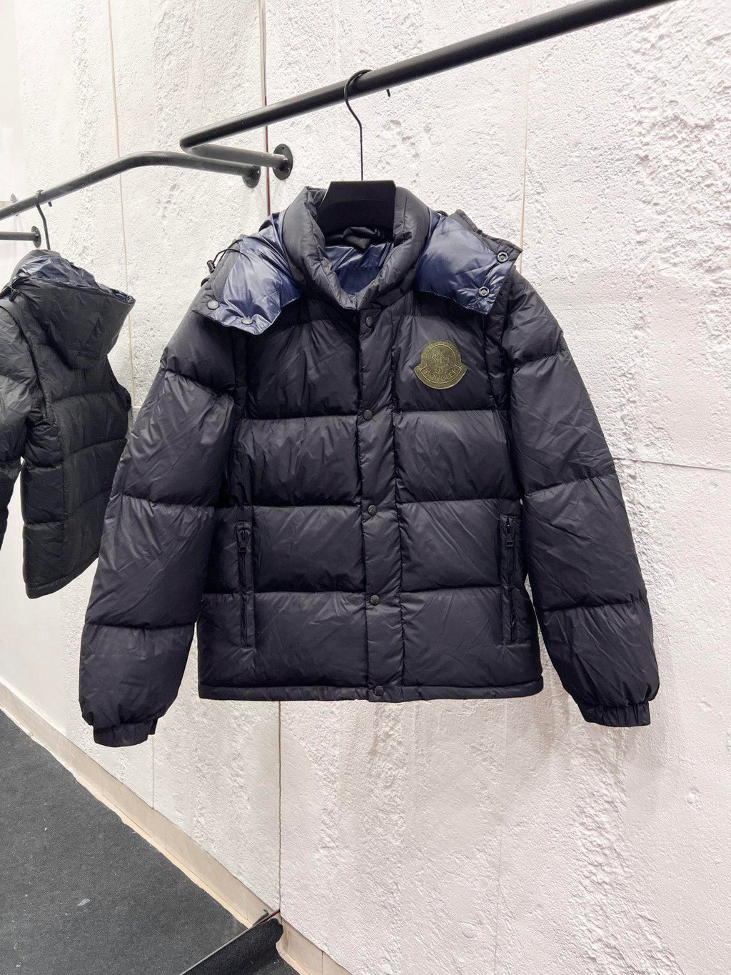 Moncler long puffer jacket on hanger, dark outer with quilted body, hood, logo badge