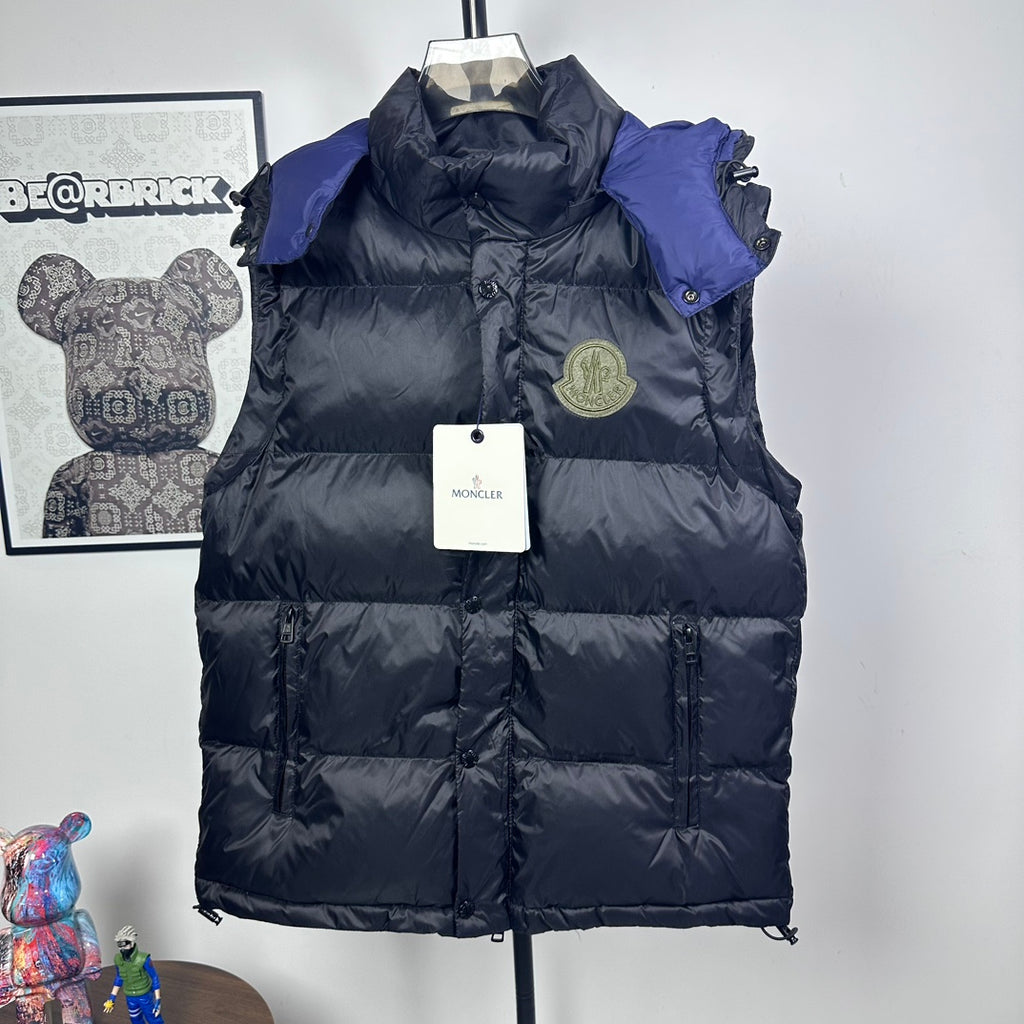 Moncler long puffer jacket front view, dark with blue hood lining, logo badge, zip closure